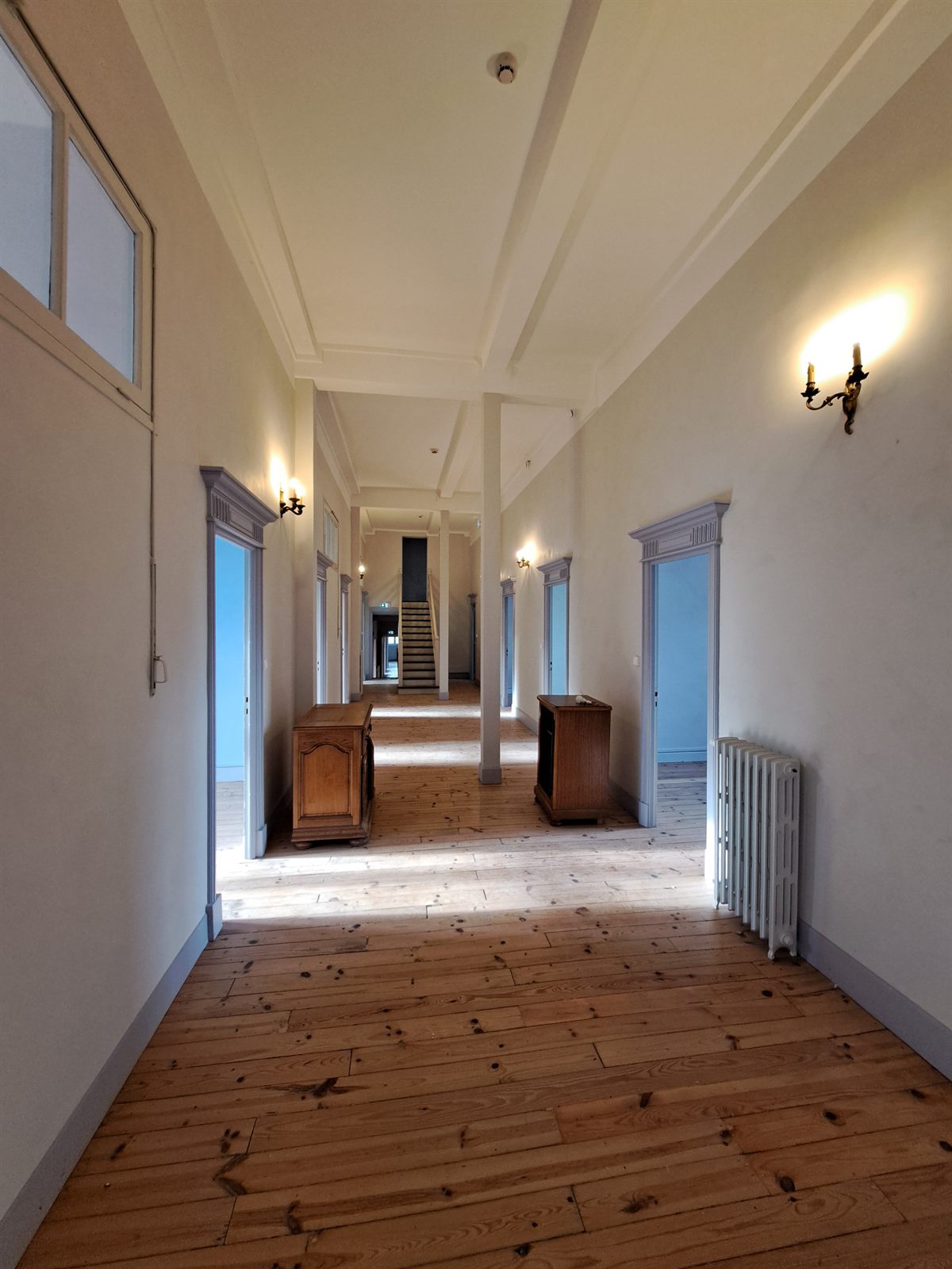 An upper-floor corridor with bedroom doors in line along a pine floor.