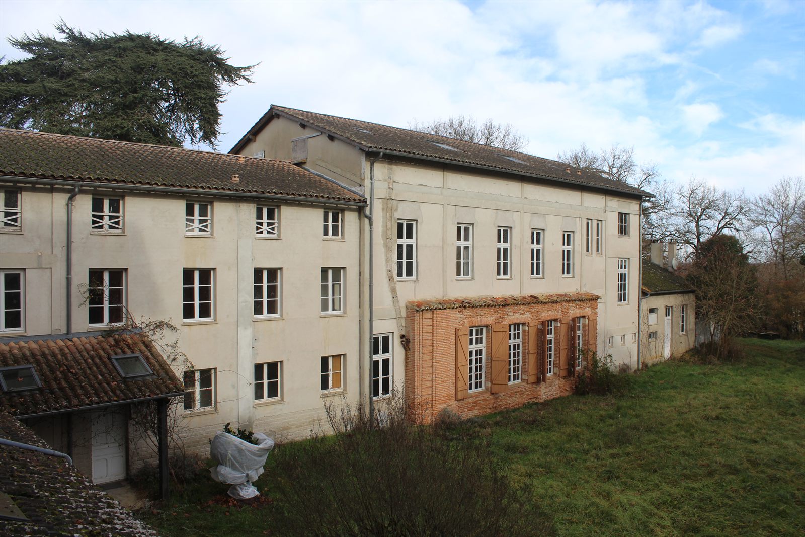 The long rendered elevation of the residency building, with a brick-faced range beside it.